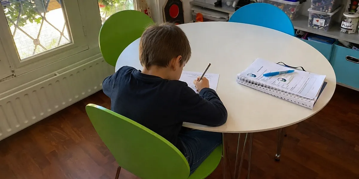 Kind maakt schoolwerk aan de tafel in de praktijkruimte